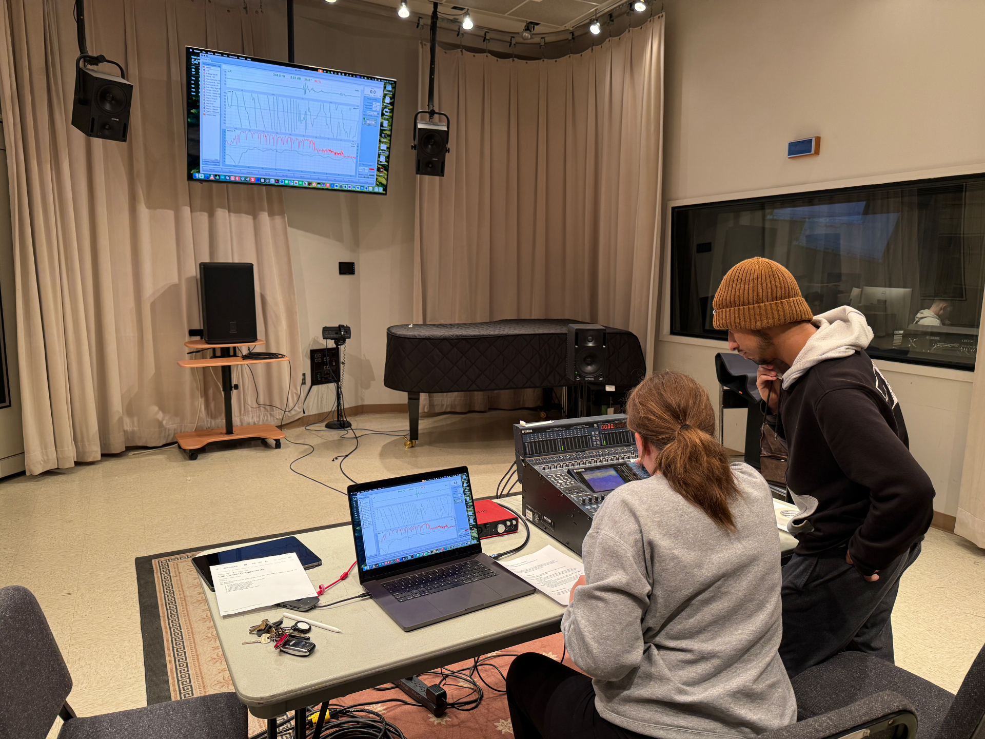 Students running a system-tuning measurement with Smaart displayed on a large screen and a laptop, alongside a Yamaha console and loudspeakers in a rehearsal room.