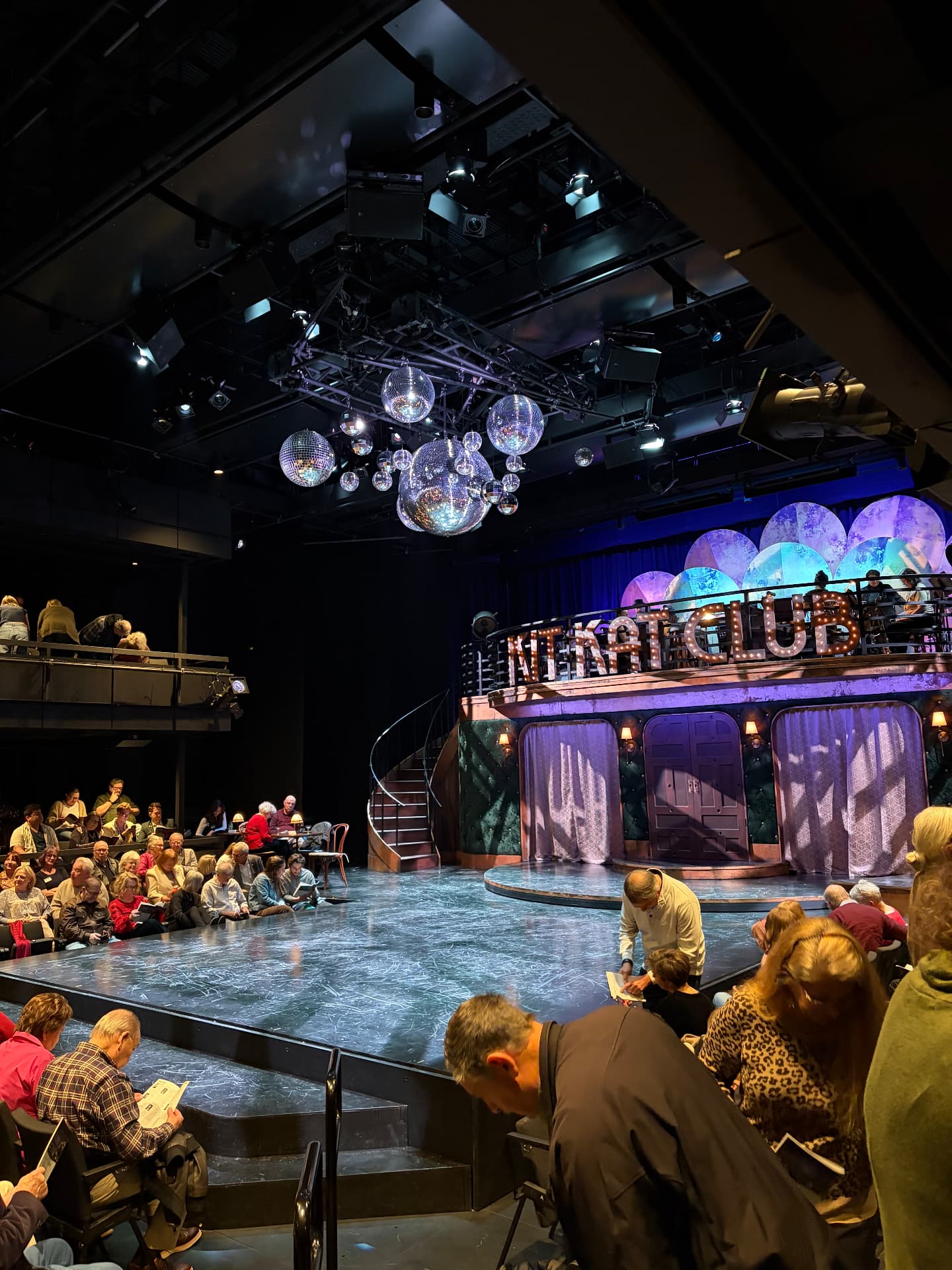 Balcony view showing the shared overhead grid serving audio, lighting, and rigging across the round.