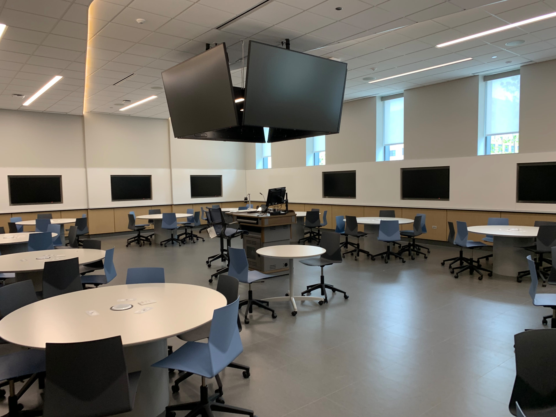 Team-based classroom with ceiling-hung displays and perimeter monitors.