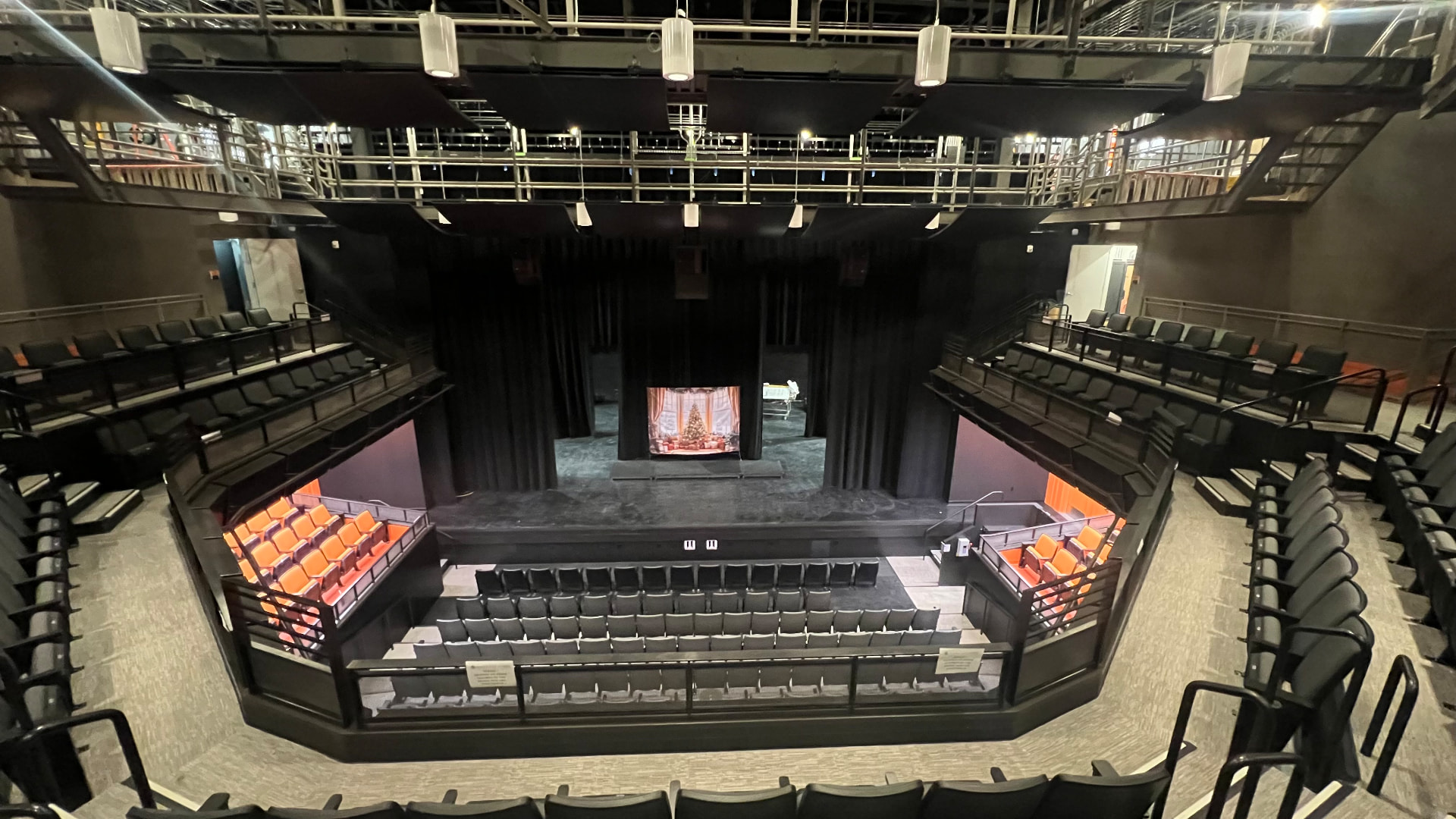 View from the balcony toward the stage, showing overhead loudspeaker positions on the catwalk.