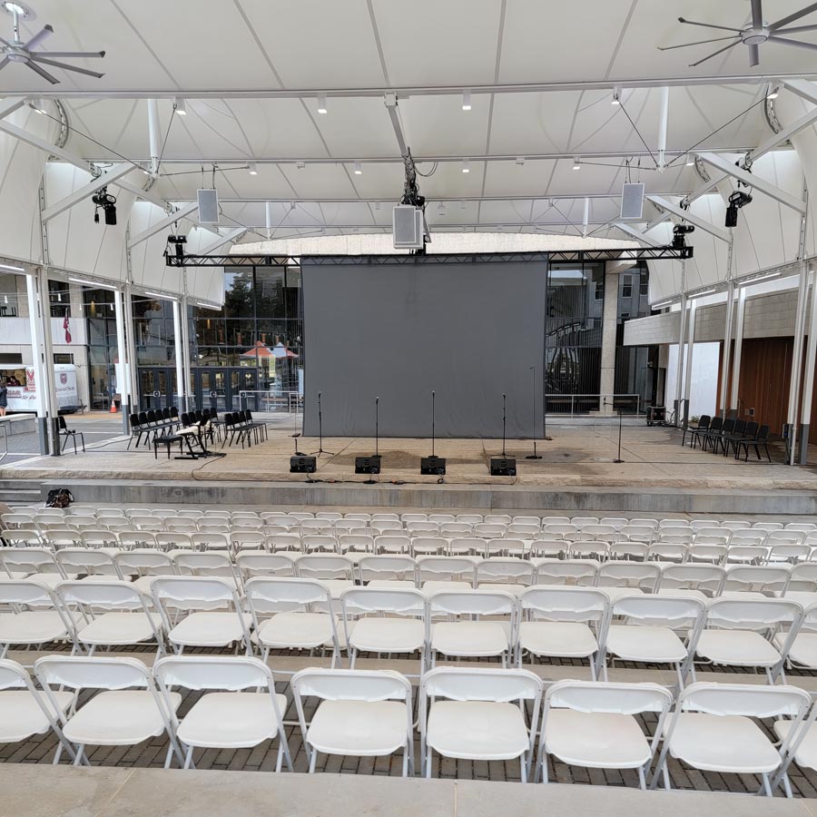Stage set for a ceremony — canopy-mounted loudspeakers, theatrical fixtures, and floor monitors.