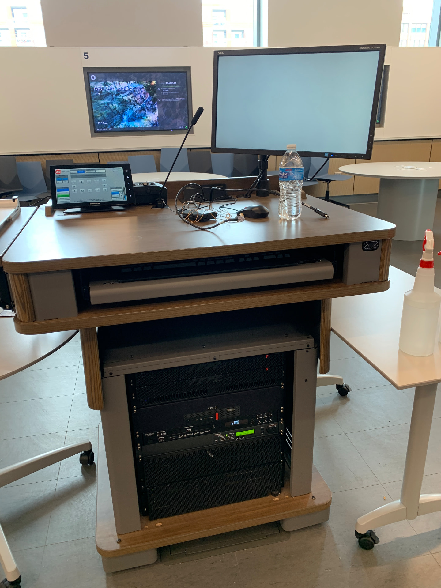 Instructor lectern with touch-panel control, gooseneck mic, and equipment rack.